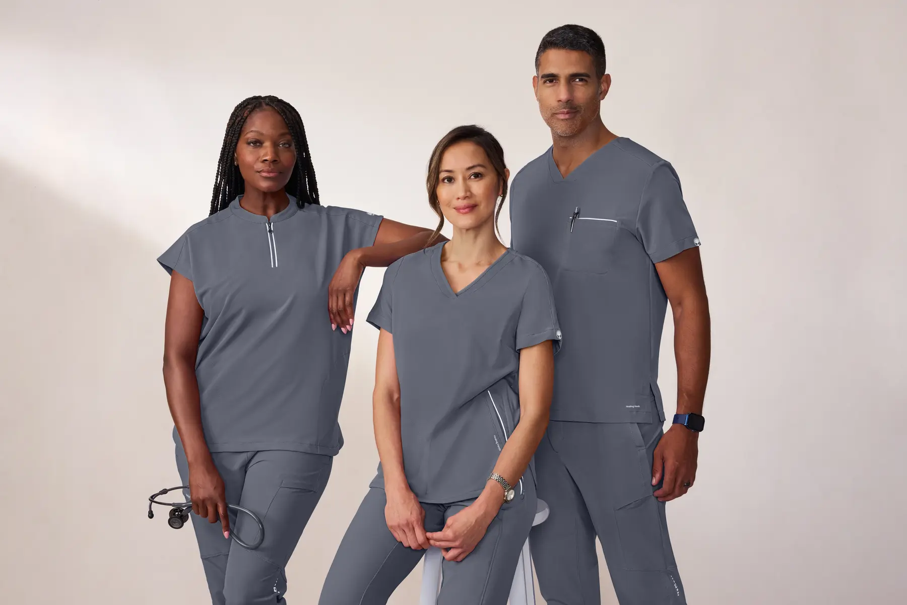 Three Kilato Uniform Group team members wearing coordinated grey scrubs, standing together in a studio setting